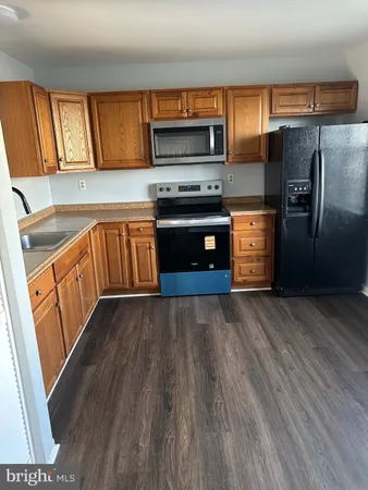 a kitchen with granite countertop a refrigerator and a stove top oven