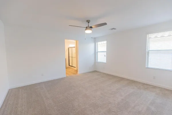 an empty room with windows and fan