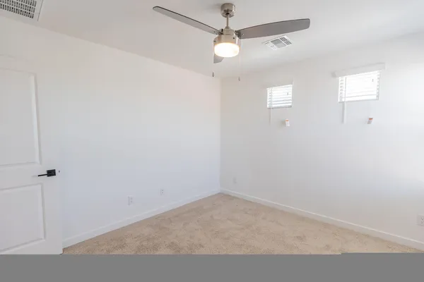 en empty room with windows and ceiling fan