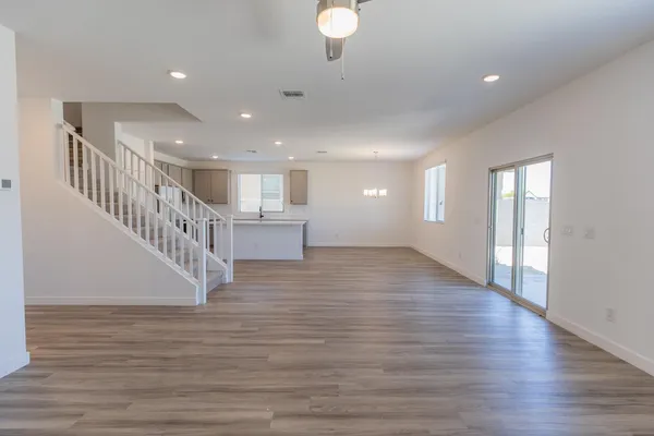a view of an empty room with wooden floor and windows
