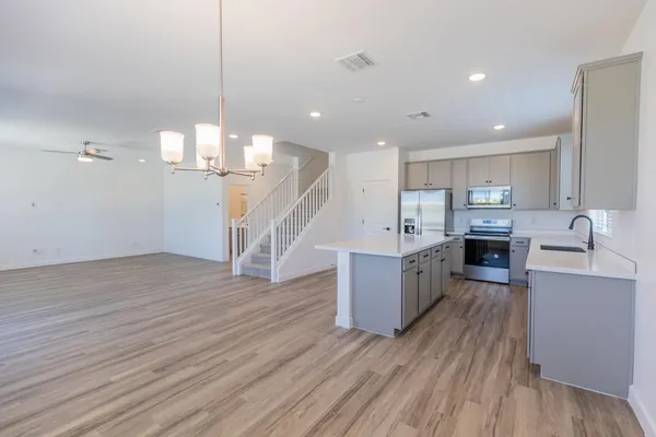 a large kitchen with a center island wooden floor stainless steel appliances and a living room view