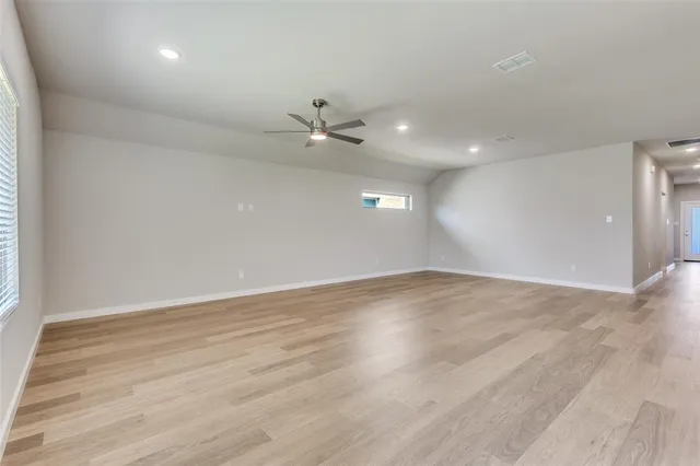 an empty room with wooden floor fan and windows