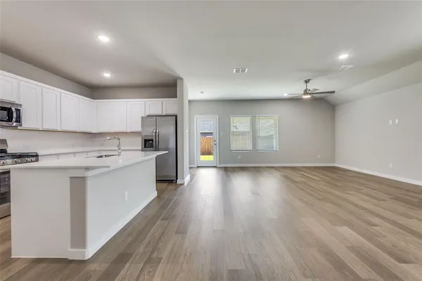 a large kitchen with stainless steel appliances lots of counter space and wooden floor