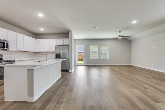 a large kitchen with stainless steel appliances lots of counter space and wooden floor