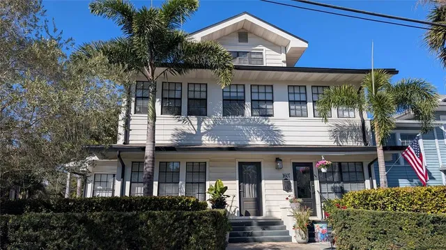 a front view of a house with glass windows and plants