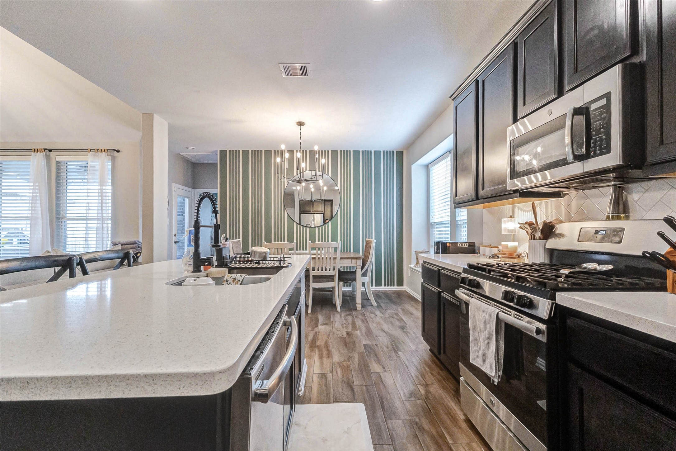 3210 Montclair Orchard Trace Spring, TX 77386 - Photo 15 of 38 a kitchen with stainless steel appliances granite countertop a stove top oven a sink dishwasher a dining table and chairs with wooden floor