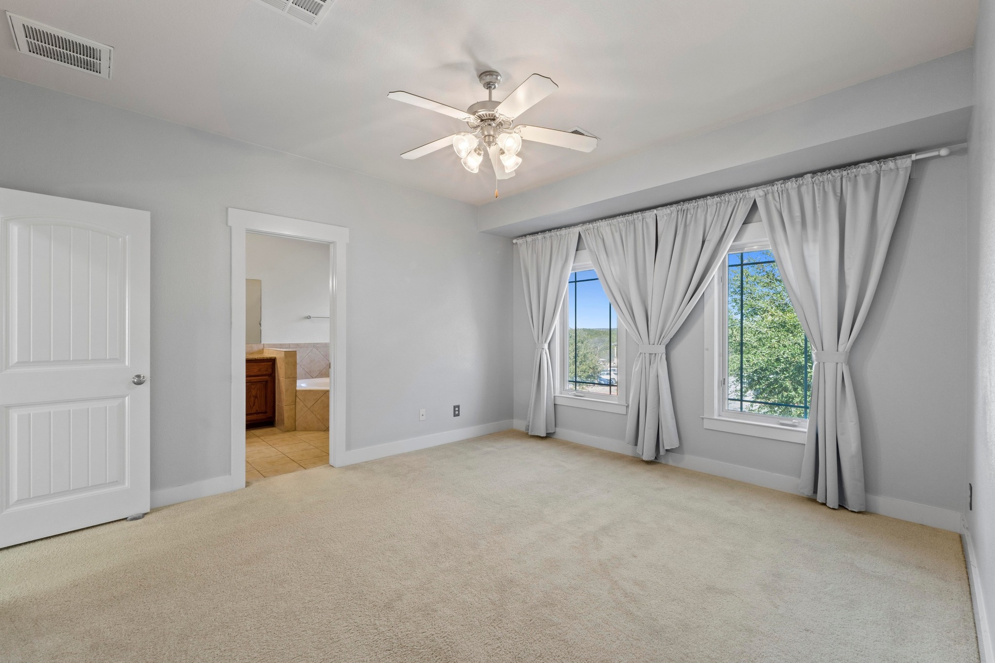 2930 Grand Oaks Loop, Unit 603 Cedar Park, TX 78613 - Photo 14 of 29 Large primary bedroom with light carpet, ensuite bath, and a ceiling fan, walk-in closet