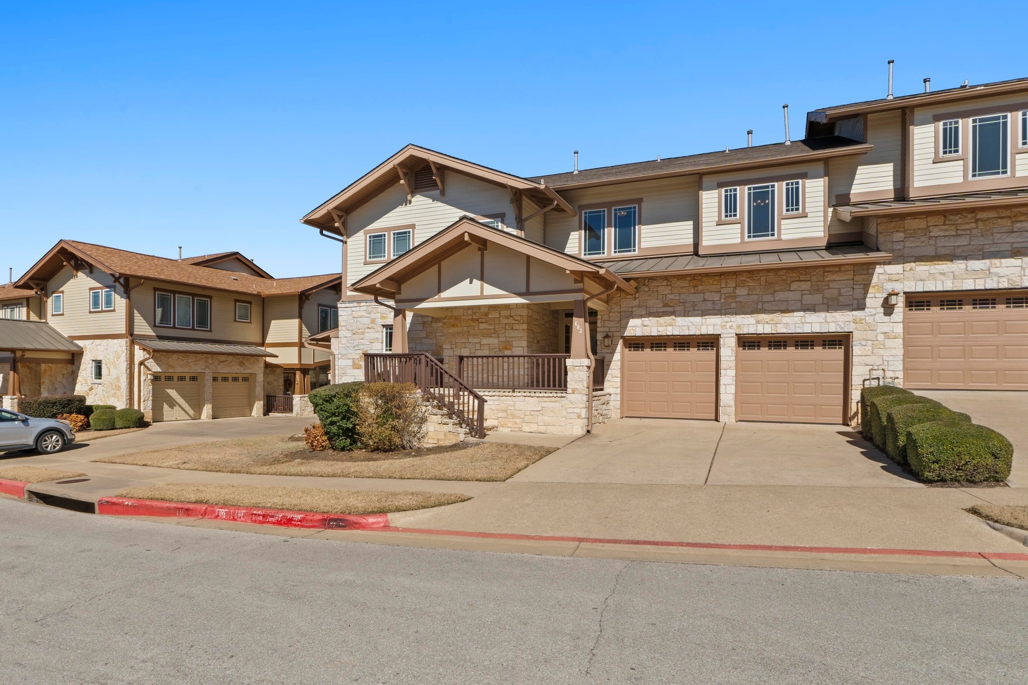 2930 Grand Oaks Loop, Unit 603 Cedar Park, TX 78613 - Photo 2 of 29 View of front facade with an attached garage, concrete driveway, stone siding, a standing seam roof, and a residential view