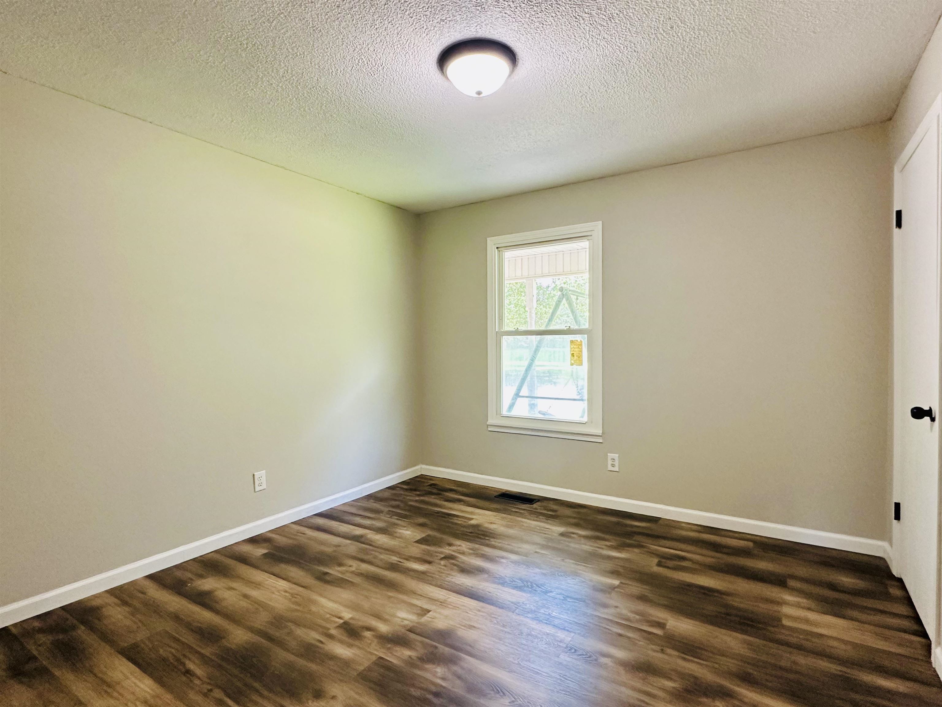 287 Gilchrist Stantonville Road Adamsville, TN 38310 - Photo 19 of 29 Spare room with dark wood-type flooring and a textured ceiling