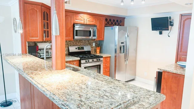 a kitchen with stainless steel appliances granite countertop a refrigerator a stove and a sink