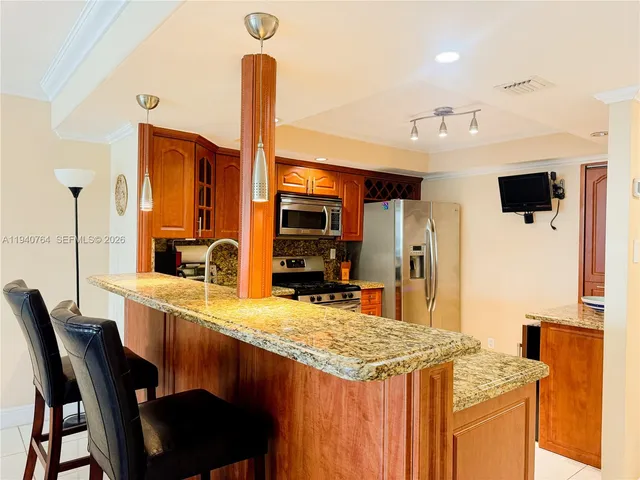 a kitchen with stainless steel appliances kitchen island granite countertop a table chairs in it and wooden floors
