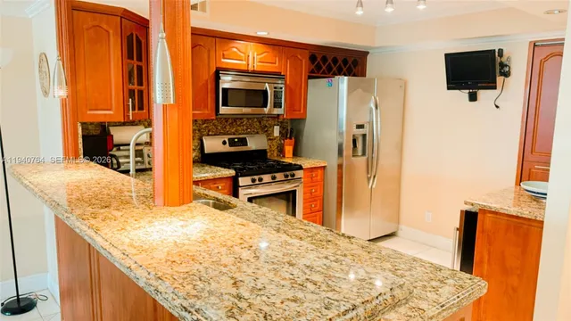 a kitchen with stainless steel appliances granite countertop a refrigerator and a stove top oven