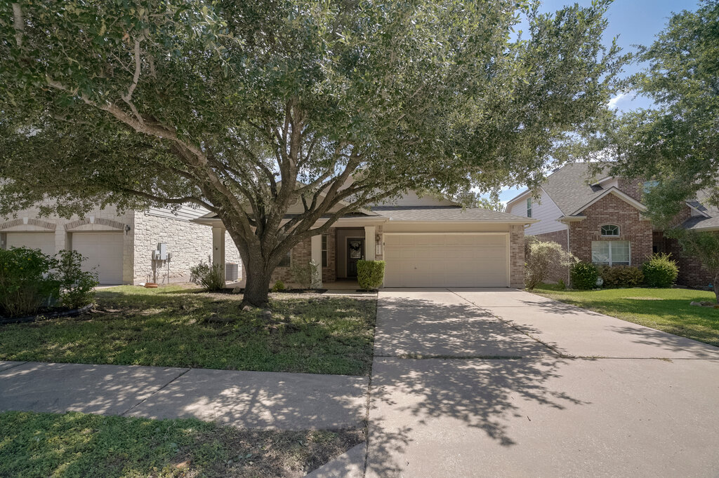 2724 Kickapoo Cavern Drive Pflugerville, TX 78660 - Photo 2 of 24 A well-maintained facade features a welcoming entrance and ample driveway space, framed by mature trees.