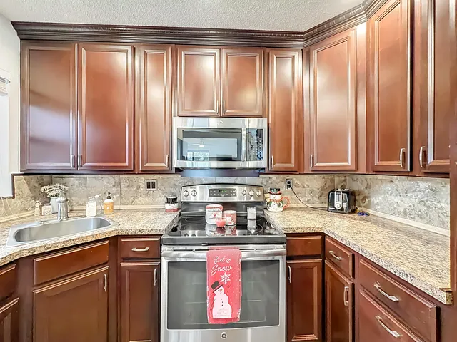 a kitchen with stainless steel appliances granite countertop a refrigerator a stove and a sink