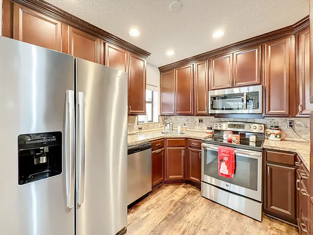 a kitchen with stainless steel appliances granite countertop a refrigerator a sink and wooden cabinets