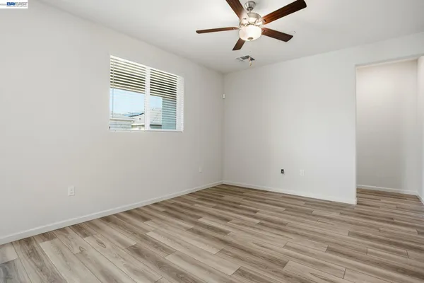 an empty room with wooden floor fan and windows