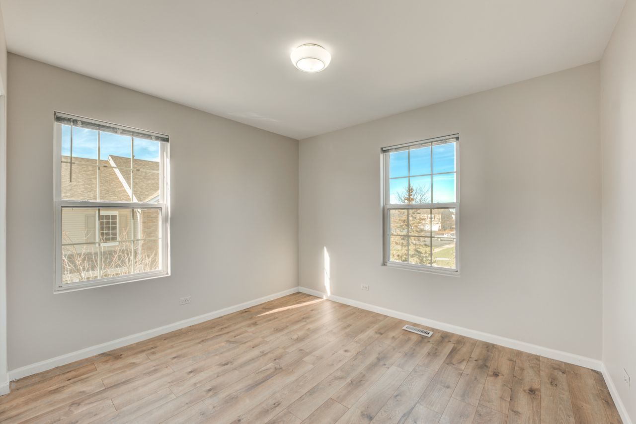 277 Springbrook Trail South Oswego, IL 60543 - Photo 22 of 28 an empty room with wooden floor and windows