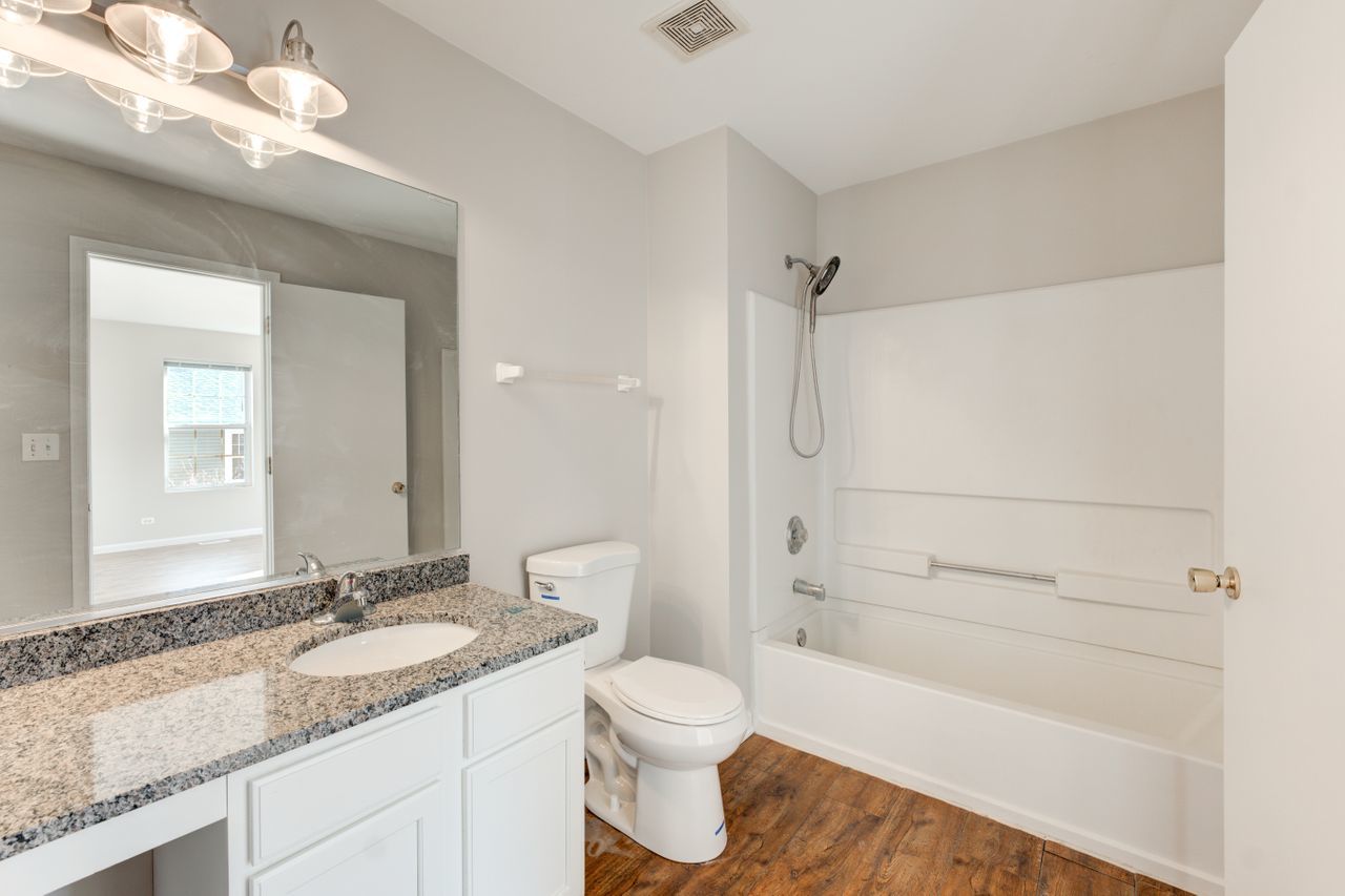277 Springbrook Trail South Oswego, IL 60543 - Photo 24 of 28 a bathroom with a granite countertop sink a toilet and bathtub