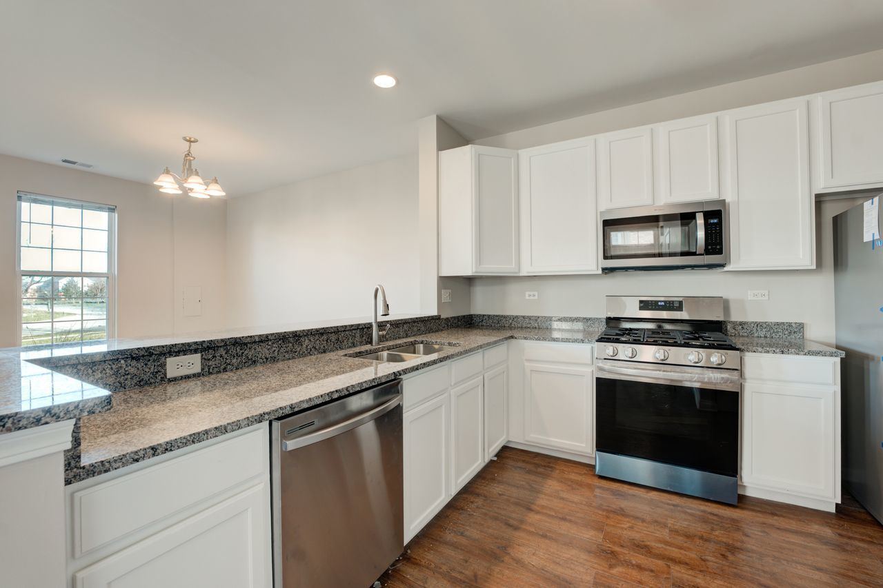 277 Springbrook Trail South Oswego, IL 60543 - Photo 3 of 28 a kitchen with stainless steel appliances granite countertop a stove a sink and a microwave