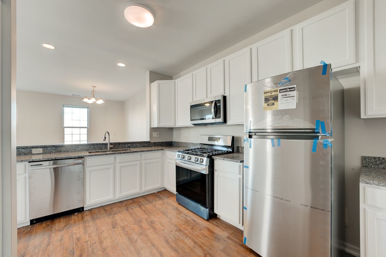 277 Springbrook Trail South Oswego, IL 60543 - Photo 4 of 28 a kitchen with stainless steel appliances granite countertop a refrigerator a stove top oven a sink and dishwasher with wooden floor