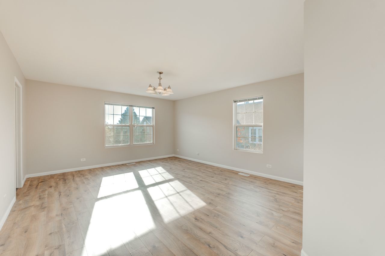 277 Springbrook Trail South Oswego, IL 60543 - Photo 9 of 28 an empty room with wooden floor and windows