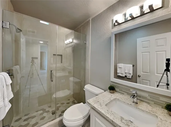 a bathroom with a granite countertop sink toilet a shower and a mirror