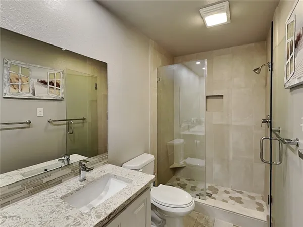 a bathroom with a granite countertop sink toilet and shower