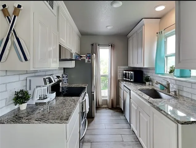 a kitchen with kitchen island granite countertop a sink stove and cabinets