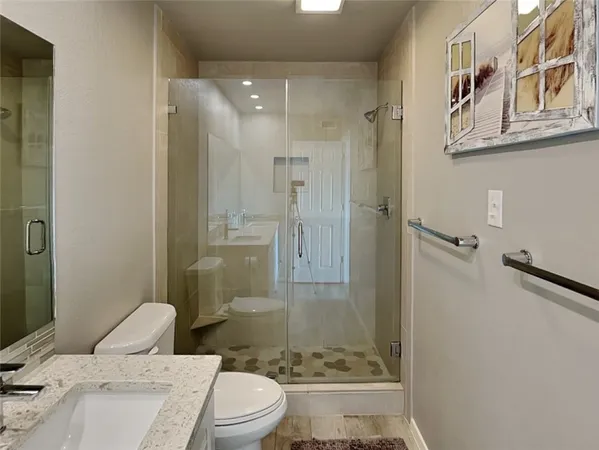 a bathroom with a granite countertop toilet a sink and shower