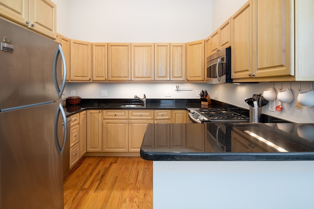 11 Wyman Street, Unit 2B Boston, MA 02130 - Photo 3 of 11 a kitchen with stainless steel appliances granite countertop a refrigerator sink and white cabinets