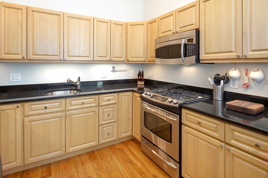 11 Wyman Street, Unit 2B Boston, MA 02130 - Photo 4 of 11 a kitchen with granite countertop white cabinets and stainless steel appliances
