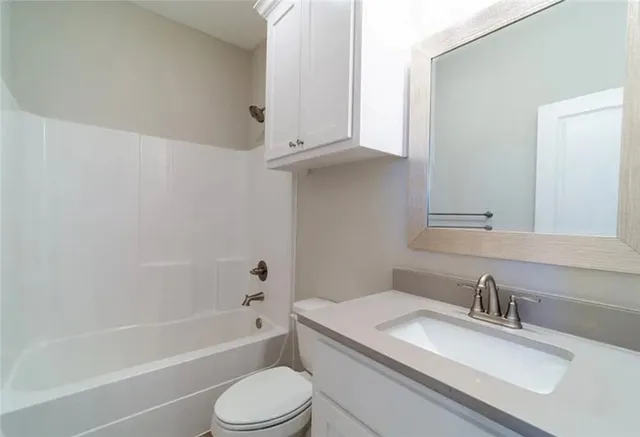 a bathroom with a granite countertop sink toilet and bathtub