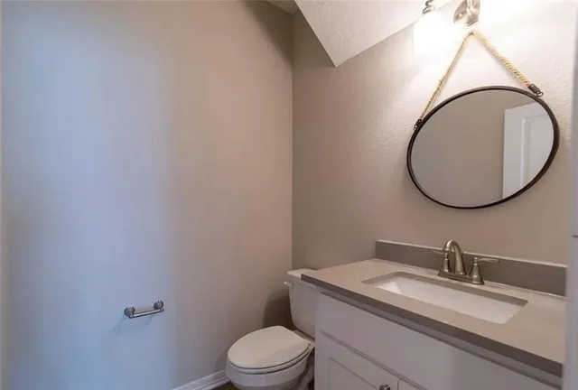a bathroom with a granite countertop toilet a sink and a mirror