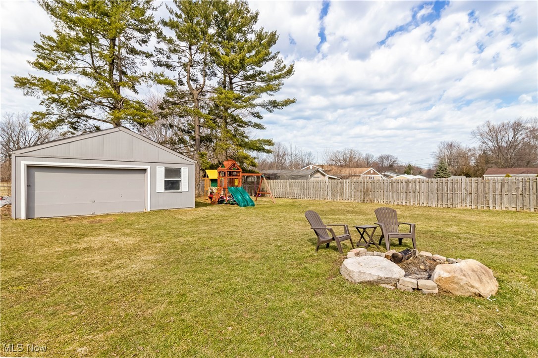 5900 Lear Nagle Road North Ridgeville, OH 44039 - Photo 32 of 35 View of yard featuring an outbuilding, fence, a fire pit, a garage, and a playground