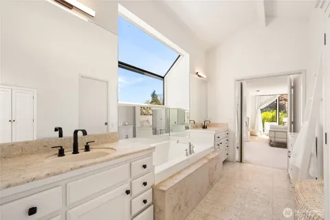 a bathroom with a granite countertop tub sink and mirror