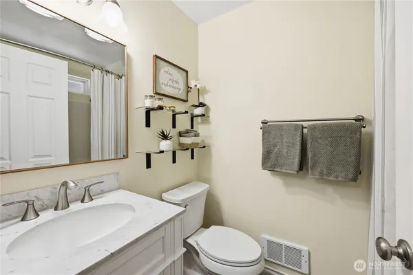 a bathroom with a toilet sink vanity shower and mirror