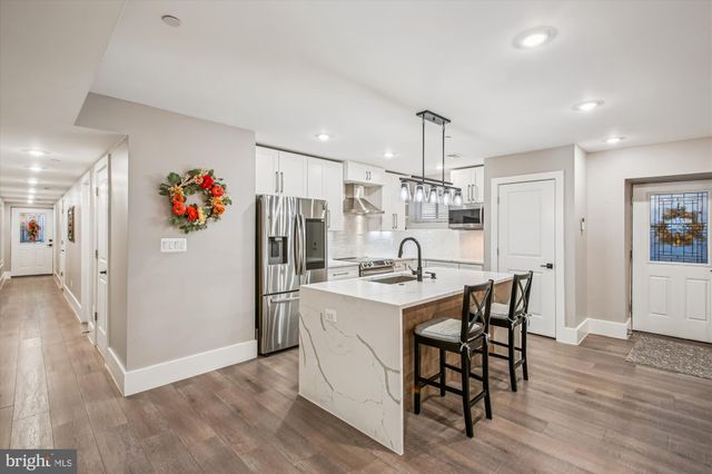a kitchen with stainless steel appliances a dining table chairs and wooden floor