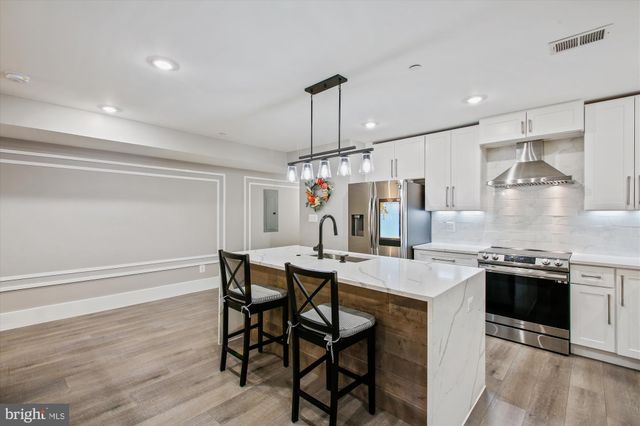 a kitchen with stainless steel appliances granite countertop a kitchen island hardwood floor and chairs