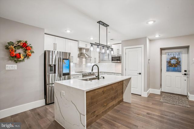 a kitchen with stainless steel appliances granite countertop a sink a refrigerator a stove and white cabinets with wooden floor