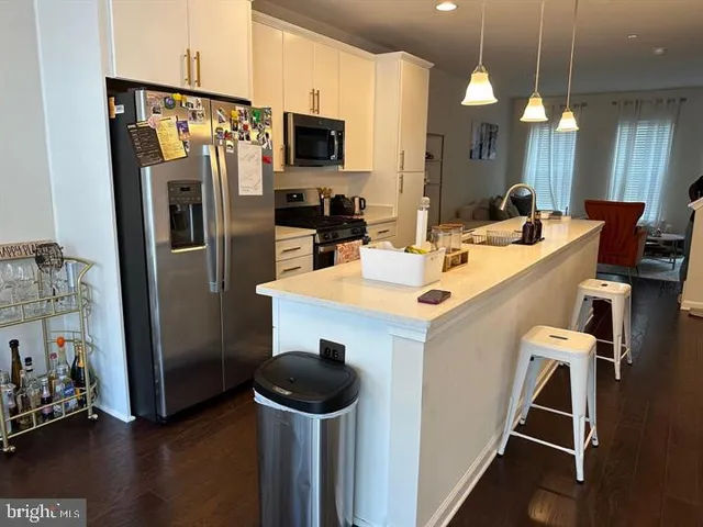 a kitchen with a refrigerator a stove a sink and a dining table with wooden floor