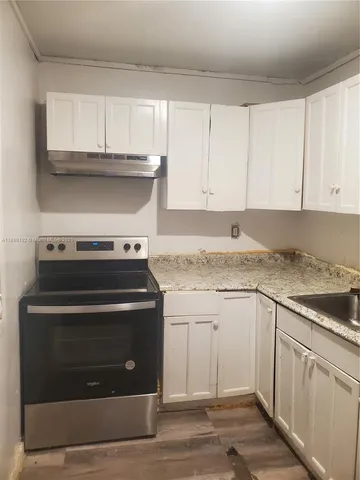 a kitchen with granite countertop white cabinets and a stove