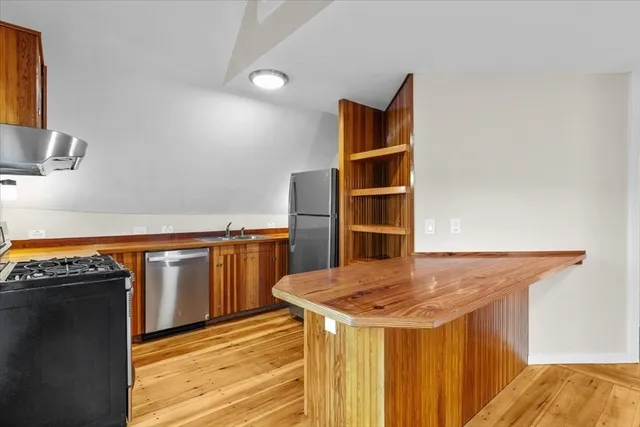 a kitchen with stainless steel appliances cabinets and wooden floor