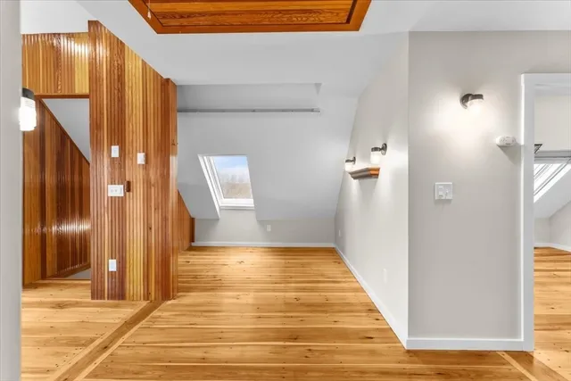a view of a hallway with wooden floor and a bathroom