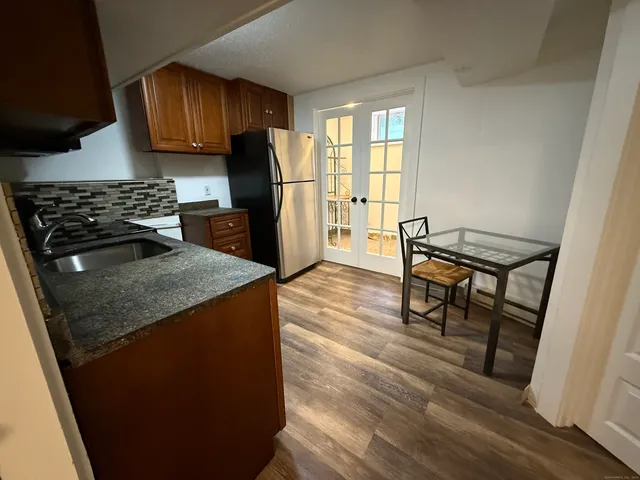 a kitchen with granite countertop a stove a refrigerator and wooden floor