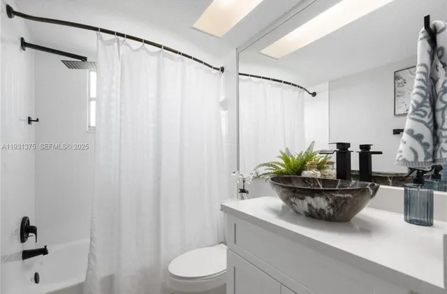 a bathroom with a granite countertop sink a toilet and shower