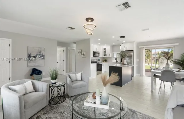 a living room with furniture kitchen view and a chandelier