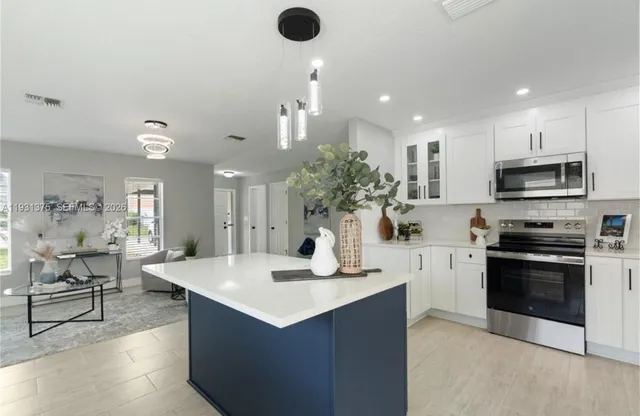 a kitchen with kitchen island white cabinets and stainless steel appliances