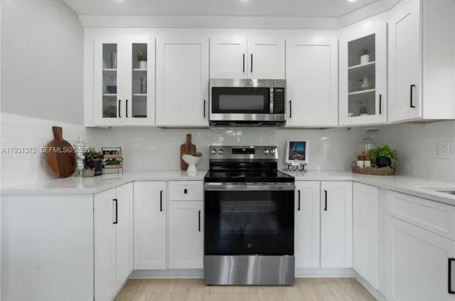 a kitchen with stainless steel appliances granite countertop white cabinets a stove top oven and granite counter tops