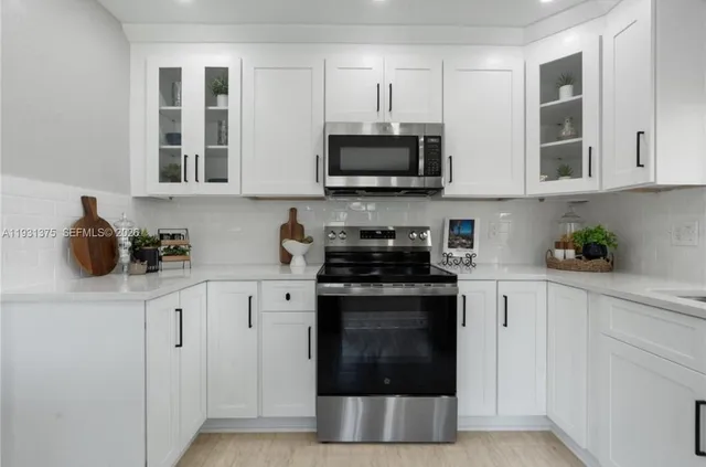 a kitchen with stainless steel appliances granite countertop white cabinets a stove top oven and granite counter tops