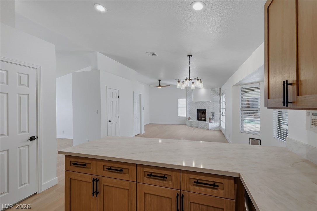 434 Crestway Road Henderson, NV 89015 - Photo 46 of 46 Kitchen with light countertops, a peninsula, open floor plan, light wood-type flooring, and a fireplace